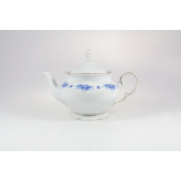 Porcelanowy czajnik Ćmielów G540 Alaska o pojemności 1,15 l. Białe naczynie z delikatnym niebieskim wzorem kwiatowym, złotym wykończeniem krawędzi i pokrywką.