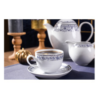 Zestaw kawowy Classic Kobalt WA-160 marki Waza. Biała filiżanka z niebieskim, kwiatowym wzorem na spodku, w tle dzbanek i mlecznik z tej samej porcelanowej