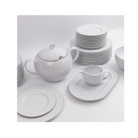 Zestaw obiadowy dla 12 osób Classic Carmen WA-91 marki Waza. Biała porcelana z delikatnym, szarym wzorem kropek, obejmująca talerze, wazę i sosjerkę na tacy.