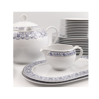 Zestaw obiadowy dla 12 osób Classic Kobalt WA-160 marki Waza. Biała porcelana z niebieskim kwiatowym wzorem, obejmująca wazę, sosjerkę, półmiski i stos talerzy.