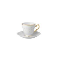 Porcelanowy spodek 14 cm z kolekcji BN07 Alaska Blask Świąt marki Ćmielów. Białe naczynie zdobione delikatnym złotym wzorem gwiazdek, widoczne pod filiżanką.
