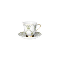 Filiżanka ze spodkiem z zestawu kawowego Ćmielów ASTRA Meander G904. Biała porcelana z zielonym roślinnym wzorem, złotym rantem i dekoracyjną złotą podstawą.