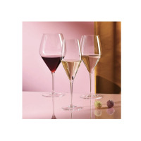 Trzy eleganckie kieliszki do wina Excellence Symphony od Krosno Glass S.A. na różowym tle. Smukłe, szklane naczynia wypełnione winem stoją obok dwóch pralinek.
