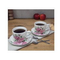 Dwie porcelanowe filiżanki 250 ml ze spodkiem Kaczyński Sp.J. CR2-69 z motywem róż, ustawione na drewnianym blacie obok dwóch łyżeczek i kruchych ciastek.