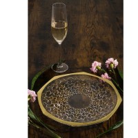 Talerz kryształowy Bohemia Arabesque Gold o średnicy 30 cm z misternym złotym wzorem, ustawiony na ciemnym drewnianym blacie obok kieliszka i kwiatów.