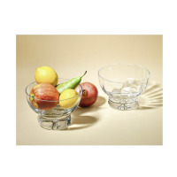 Dwie szklane salaterki z optykiem Krosno Glass o średnicy 18 cm. Jedna wypełniona owocami: jabłkiem, cytrynami, gruszką i granatem, druga pusta, ustawiona obok.