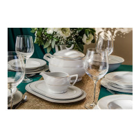 Elegancki zestaw obiadowy dla 12 osób Gracja WA-151 marki Waza. Biała porcelana ze złotym zdobieniem, waza, sosjerka i talerze na zielonym obrusie ze złotą