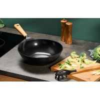 Czarna patelnia wok 28 cm NATUR marki Gerlach z drewnianą rączką na kuchennym blacie obok deski z brokułami i akcesoriami kuchennymi z logo Gerlach.