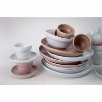 Różowy spodek 12 cm z kolekcji Rustic Reborn marki Verlo w zestawieniu z pasującą filiżanką oraz stosem ceramicznych naczyń w odcieniach różu i bieli.