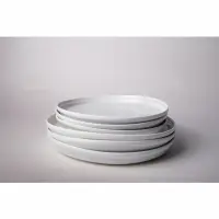Stos perłowych talerzy płytkich 23 cm z kolekcji Rustic Reborn marki Verlo. Naczynia o minimalistycznym designie ułożone w pionie na jasnym tle.