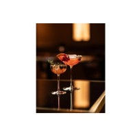 Dwa eleganckie kieliszki Schott Zwiesel Rooftop 170 ml z koktajlami, udekorowane owocami i ziołami, ustawione na ciemnym, błyszczącym blacie z odbiciami.