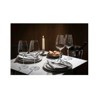Eleganckie kieliszki Schott Zwiesel Perfect Match o pojemności 514 ml na nakrytym stole z talerzami, sztućcami, świecą i pieczywem w nastrojowym oświetleniu.