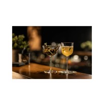 Dwa eleganckie kieliszki Schott Zwiesel na drewnianym barze. Po lewej kieliszek Martini 182 ml z serii Rooftop z oliwkami, po prawej koktajl w szkle typu coupe.