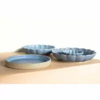 Zestaw ceramicznych naczyń Verlo w odcieniu wody: płaska misa oraz dwie karbowane salaterki o różnych średnicach ustawione na beżowym, geometrycznym tle.