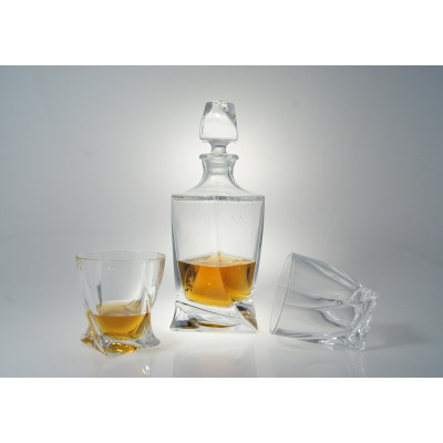 Komplet kryształowy do whisky Bohemia Quadro z karafką i dwiema szklankami o geometrycznym, skręconym kształcie. Bursztynowy trunek wewnątrz szklanego naczynia.