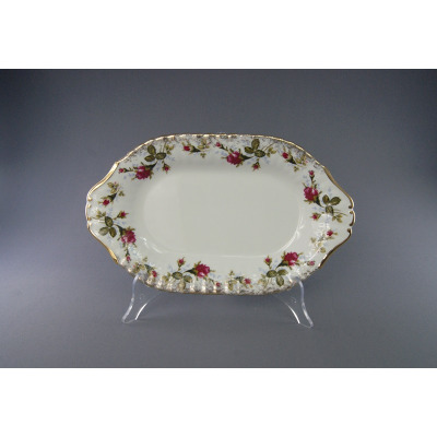 Owalny półmisek Chodzież Iwona B013 o średnicy 28 cm z kremowej porcelany, zdobiony motywem róż i złotym wykończeniem brzegów, wyeksponowany na przezroczystym