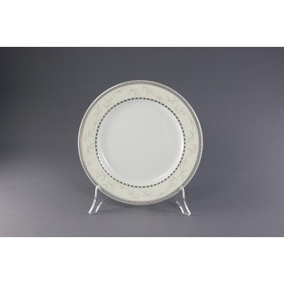 Talerz deserowy 19 cm Ćmielów B601 Astra na przezroczystym stojaku. Biała porcelana z delikatnym roślinnym wzorem i geometryczną czarno-białą obwódką na rancie.