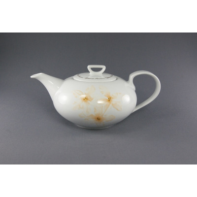Biały porcelanowy czajnik Chodzież 1,40 l z serii 9542 YVETTE. Pękaty korpus zdobi delikatny motyw kwiatowy w odcieniach beżu, a na pokrywce widnieje napis.