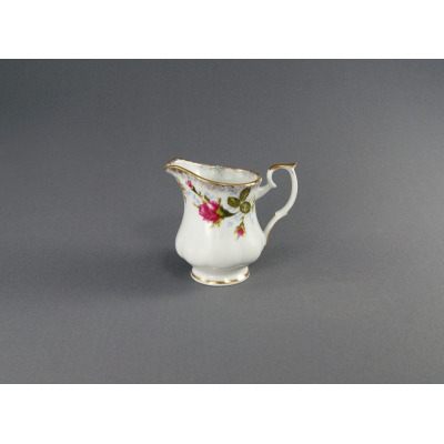 Porcelanowy dzbanek do mleczka 0,15 l Iwona Złota róża marki Chodzież. Białe naczynie z delikatnym motywem róż, wykończone złotym rantem, ukazane z profilu.