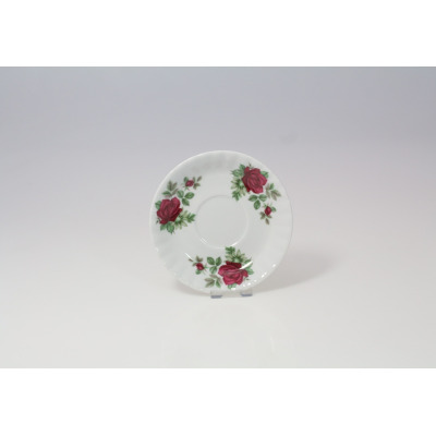 Biały porcelanowy spodek Chodzież Iwona o średnicy 14 cm z motywem bordowej róży. Klasyczny fason z delikatnym tłoczeniem na krawędziach, widok z góry.