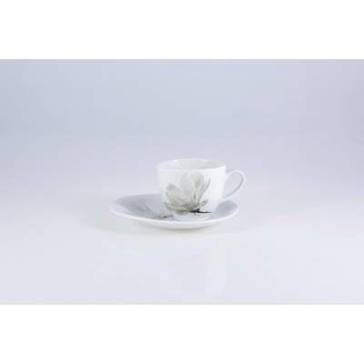 Biała porcelanowa filiżanka ze spodkiem Lubiana 6474 Magnolia o pojemności 0,20 l, ozdobiona subtelnym, szarym motywem kwiatowym na jasnym tle. Widok z profilu.