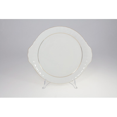 Talerz do ciasta Chodzież Iwona B014 o średnicy 24 cm. Biała porcelana z subtelną złotą linią, ozdobnymi falistymi brzegami i uchwytami, wyeksponowana na