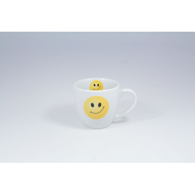 Biały porcelanowy kubek 300 ml 4067A BILL marki Lubiana z nadrukiem żółtej uśmiechniętej buźki na zewnętrznej ściance oraz mniejszą buźką wewnątrz naczynia.