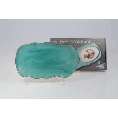 Półmisek 35 cm STONE AGE marki Lubiana w kolorze morskim. Ceramiczne naczynie o falistych brzegach i nakrapianej fakturze, ustawione na stojaku przed