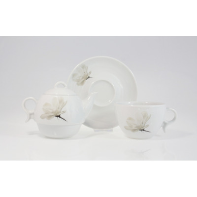 Zestaw do herbaty z czajnikiem Lubiana 6474 Magnolia. Biała porcelanowa filiżanka, spodek i czajnik z subtelnym motywem kwiatowym na jasnym, neutralnym tle.