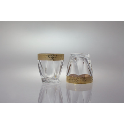 Dwie szklanki kryształowe do whisky Bohemia Quadro Rich Gold 340 ml. Jedna stoi pionowo, druga jest odwrócona dnem do góry, eksponując złoty grecki wzór.