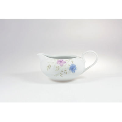 Biała porcelanowa sosjerka 0,50 l z serii G679 YVONNE marki Chodzież. Naczynie zdobi delikatny motyw kwiatowy w odcieniach różu i błękitu, widok z profilu.