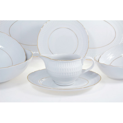 Sosjerka z serwisu obiadowego Ćmielów Sofia na spodku, wykonana z białej porcelany ze złotym rantem i tłoczonym wzorem. W tle widoczne pozostałe elementy