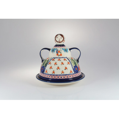 Ceramiczna baba do sera Bolesławiec 149AR o wysokości 19,2 cm. Naczynie z pokrywką zdobioną motywem kwiatów i motyli, z uchwytem w kształcie głowy postaci.