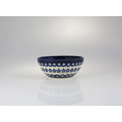 Ceramiczna salaterka Bolesławiec 166A o średnicy 14,8 cm. Naczynie zdobi tradycyjny wzór w niebieskie kwiaty i kropki na jasnym tle. Widok z boku na białym tle.