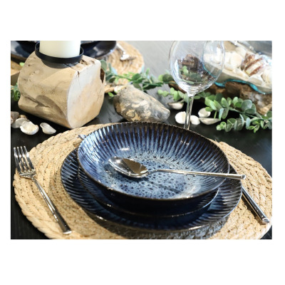 Zestaw talerzy STONEWARE S006T Cosmos marki Lubiana na plecionej podkładce. Granatowe naczynia o żłobkowanej fakturze i nakrapianym wykończeniu, widok z góry.