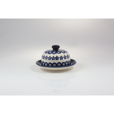 Ceramiczna maselnica Bolesławiec GU-742 z pokrywką, zdobiona tradycyjnym wzorem w niebieskie kwiaty i kółka na kremowym tle, widok z przodu na białym tle.