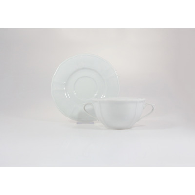 Biała bulionówka Lubiana MARIA o pojemności 300 ml z dwoma uszkami, ustawiona na dopasowanym spodku z delikatnie falowanym brzegiem. Klasyczna porcelana na