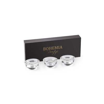 Trzy przezroczyste świeczniki kryształowe Bohemia z tealightami wewnątrz, ustawione przed czarnym pudełkiem z eleganckim złotym napisem Bohemia Prestige.