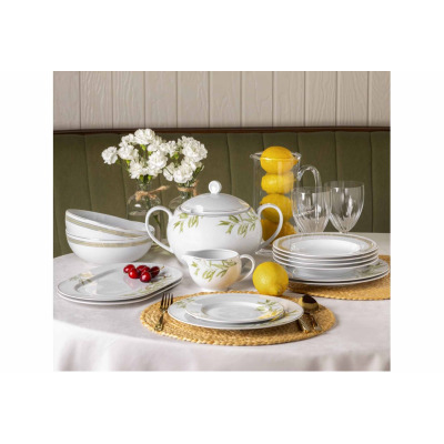 Zestaw obiadowy dla 12 osób Classic Oliwka WA-166 marki Waza. Biała porcelana z delikatnym motywem oliwnych gałązek, ustawiona na stole z wiklinowymi