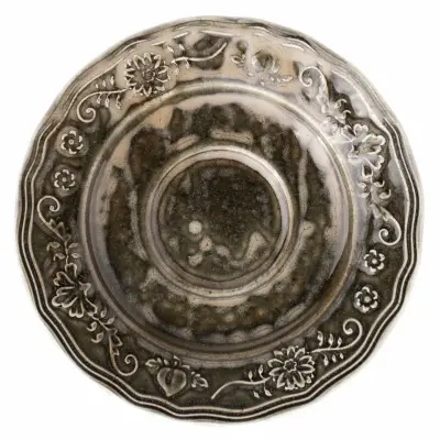 Okrągły spodek Verlo Poem Wetlands o średnicy 15 cm. Ceramiczne naczynie w odcieniach szarości i brązu z ozdobnym, reliefowym motywem kwiatowym na obrzeżach.