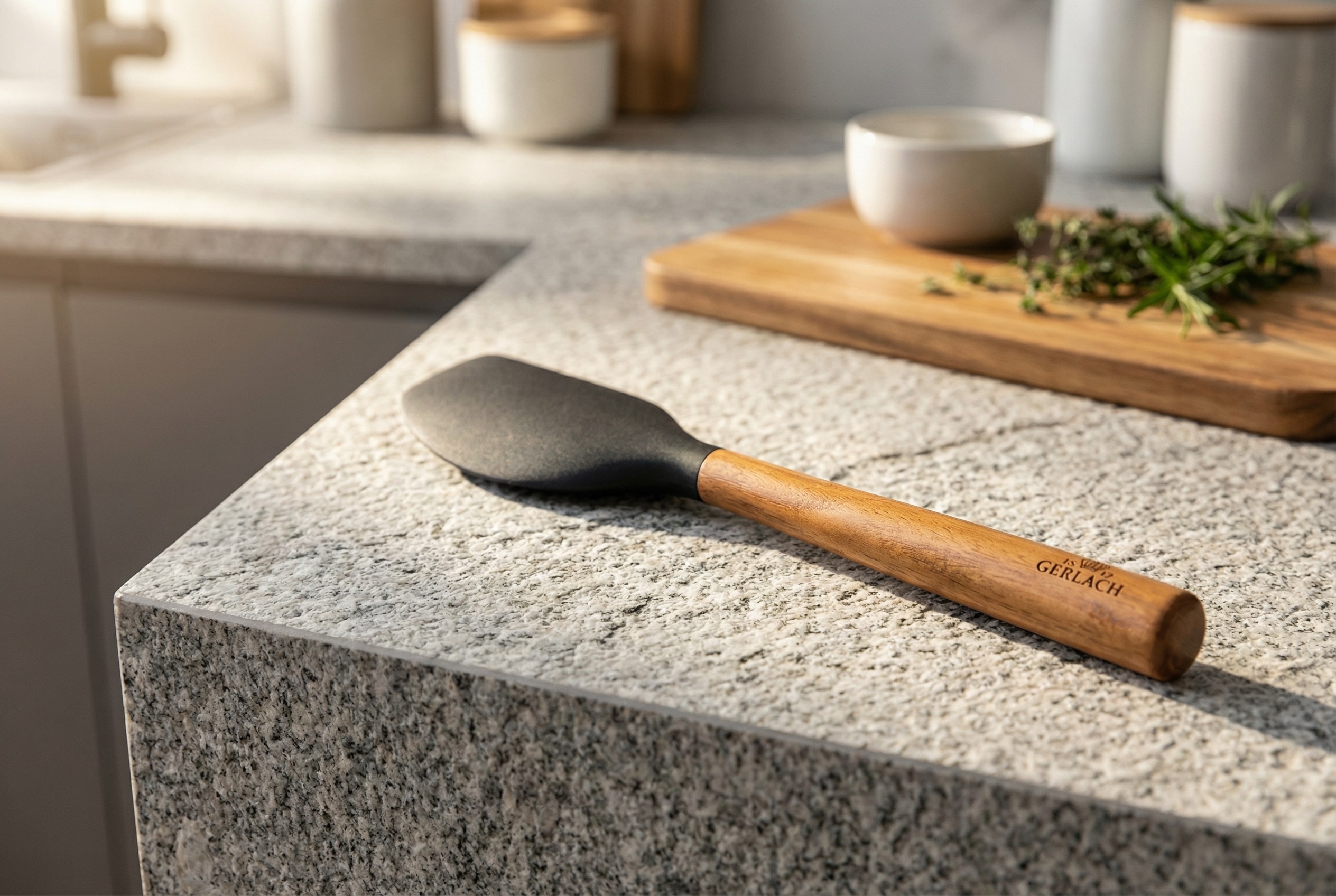 Szpatułka silikonowa kuchenna Gerlach Natur z drewnianą rączką leżąca na kamiennym blacie.